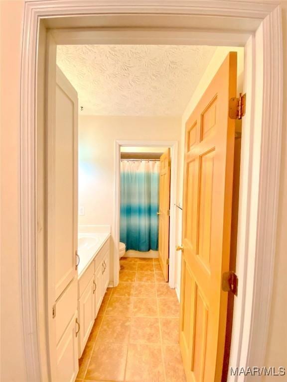 bathroom featuring tile patterned flooring, a textured ceiling, vanity, and toilet