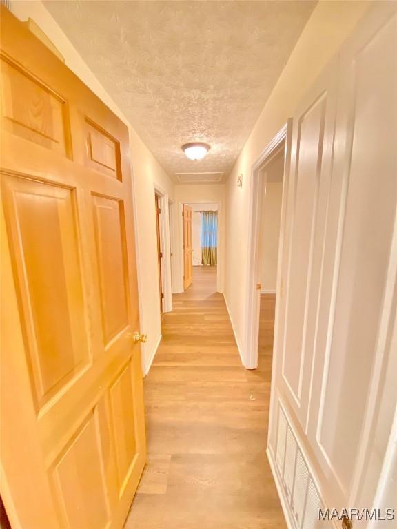 corridor featuring a textured ceiling and light wood-type flooring