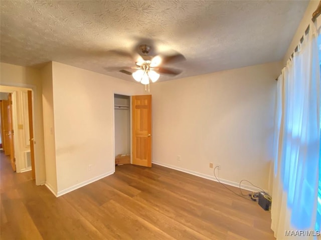 unfurnished bedroom featuring a closet, ceiling fan, hardwood / wood-style floors, and a textured ceiling