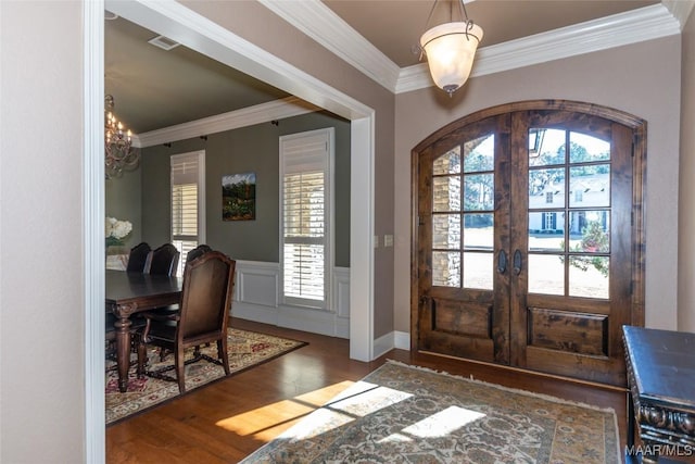 entrance foyer with french doors, dark hardwood / wood-style floors, an inviting chandelier, and ornamental molding