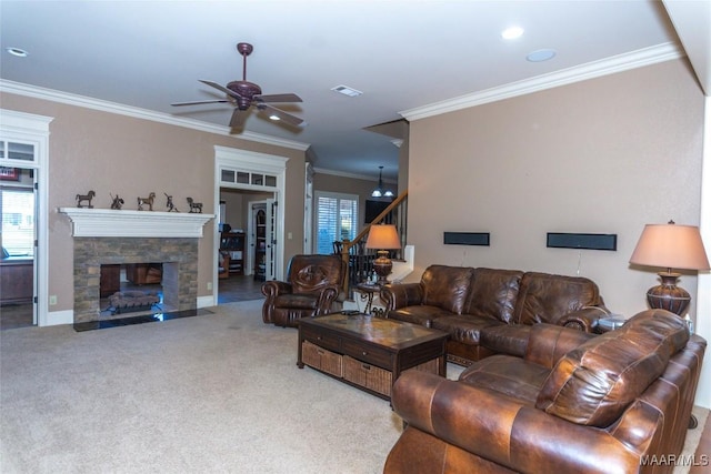 carpeted living room with a stone fireplace, ceiling fan, and ornamental molding