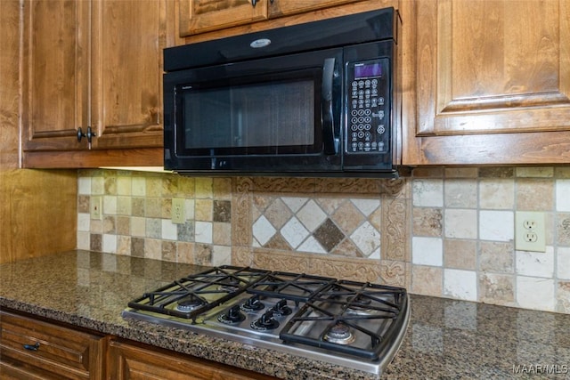 kitchen with decorative backsplash, stainless steel gas stovetop, and dark stone countertops