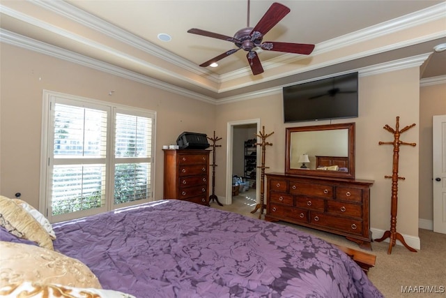 bedroom featuring light carpet, ensuite bathroom, ornamental molding, a raised ceiling, and ceiling fan