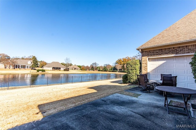 view of patio / terrace featuring a garage and a water view