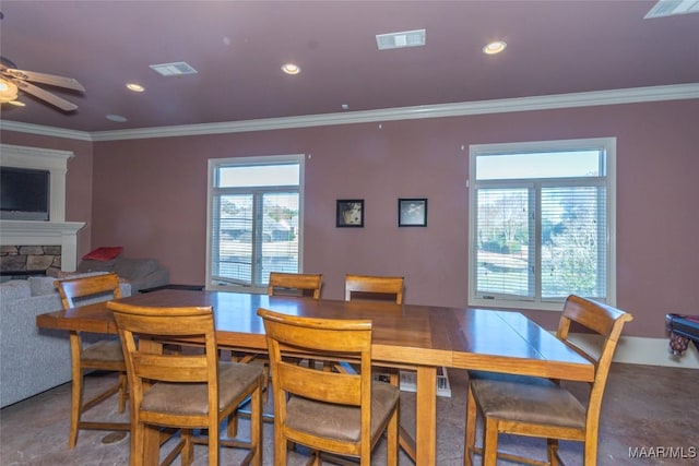 dining space featuring a fireplace, plenty of natural light, crown molding, and ceiling fan