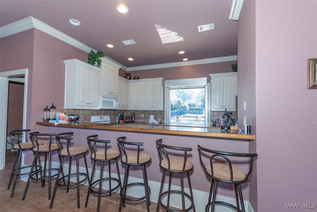 kitchen featuring a kitchen breakfast bar, kitchen peninsula, and white cabinets