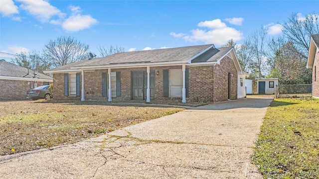 single story home with a porch, a storage shed, and a front yard