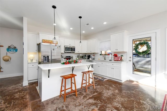 kitchen with a center island, white cabinets, decorative light fixtures, a kitchen bar, and stainless steel appliances