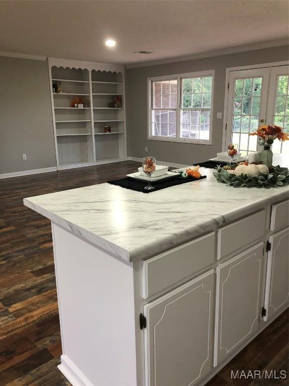 kitchen featuring white cabinets, crown molding, dark wood-type flooring, and light stone counters