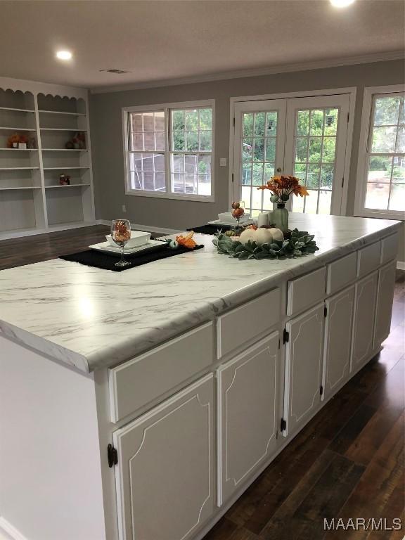 kitchen featuring white cabinetry, dark hardwood / wood-style flooring, a center island, and ornamental molding