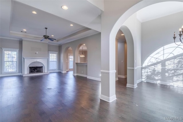 unfurnished living room with a raised ceiling, ceiling fan, dark wood-type flooring, and a tiled fireplace