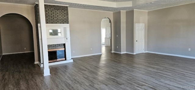 unfurnished living room featuring a textured ceiling, ornamental molding, a fireplace, and dark wood-type flooring