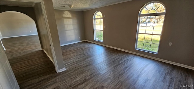 empty room with a textured ceiling, dark hardwood / wood-style flooring, and crown molding