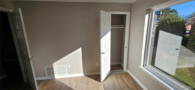 unfurnished bedroom featuring light hardwood / wood-style floors, a closet, and multiple windows