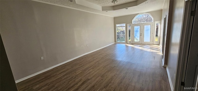 empty room with dark wood-type flooring, french doors, crown molding, a textured ceiling, and a tray ceiling