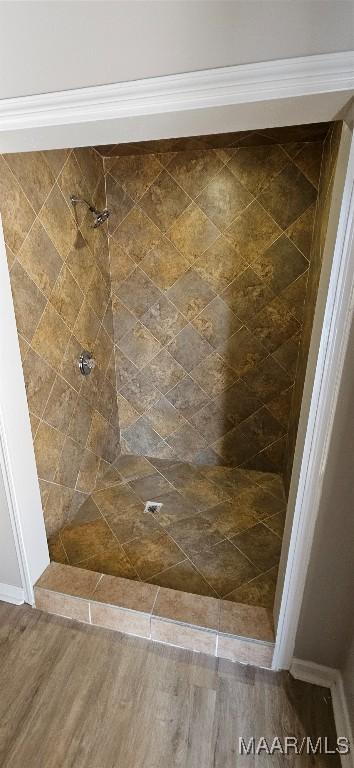 bathroom with tiled shower and hardwood / wood-style floors