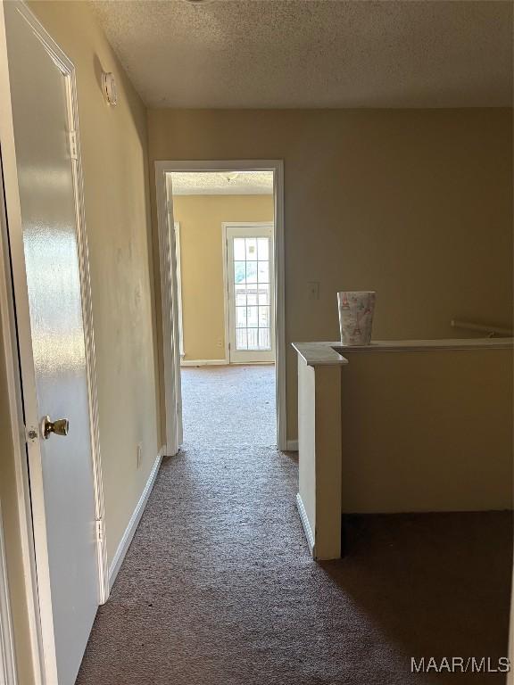 hallway with a textured ceiling and carpet flooring