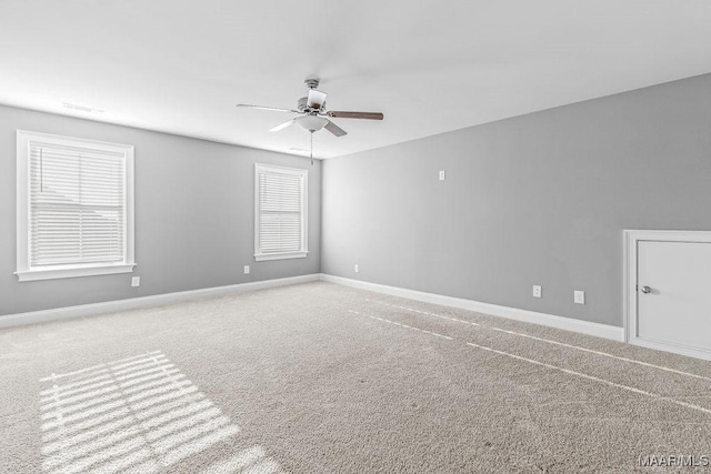 empty room featuring ceiling fan, carpet floors, and a wealth of natural light