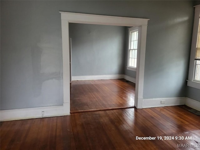 spare room featuring wood-type flooring and baseboards