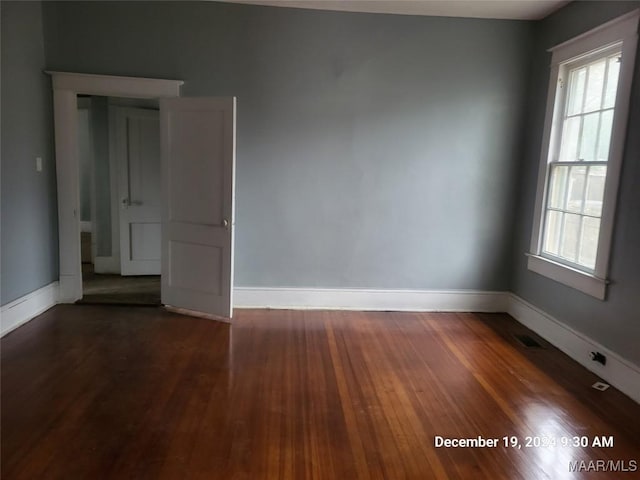 unfurnished room with visible vents, baseboards, and dark wood-style flooring