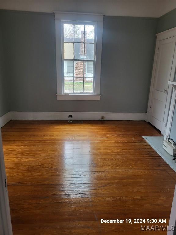 spare room with baseboards and wood finished floors