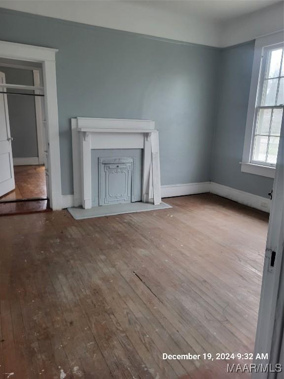 unfurnished living room with hardwood / wood-style floors and baseboards