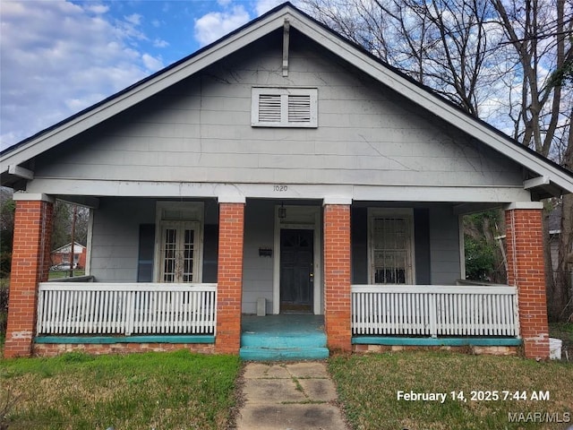 bungalow-style home with covered porch and brick siding