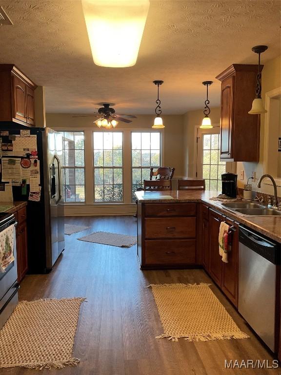 kitchen featuring ceiling fan, sink, hanging light fixtures, stainless steel appliances, and dark hardwood / wood-style floors