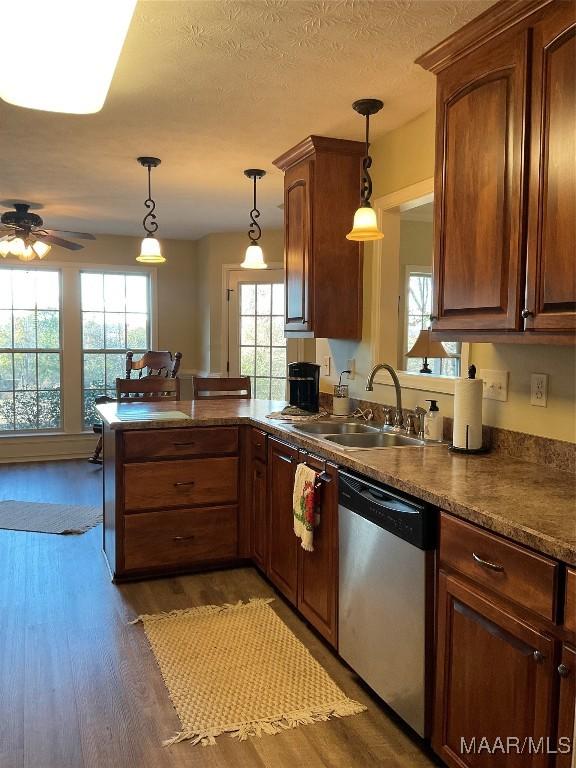 kitchen featuring kitchen peninsula, dark wood-type flooring, stainless steel dishwasher, and decorative light fixtures