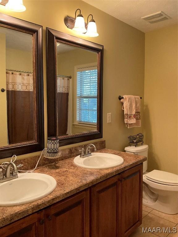 bathroom featuring tile patterned flooring, vanity, and toilet