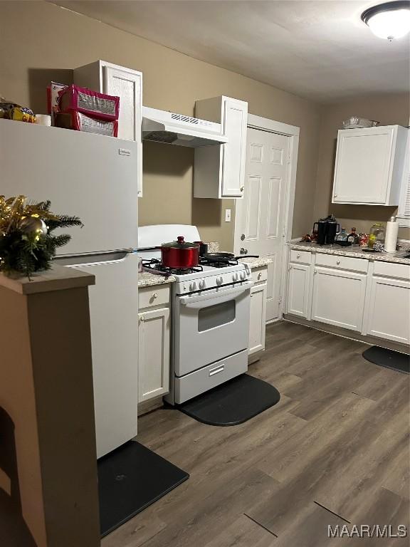 kitchen with white appliances, white cabinetry, and range hood