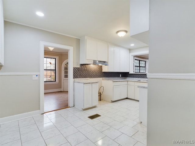 kitchen featuring white cabinets, decorative backsplash, ventilation hood, and crown molding