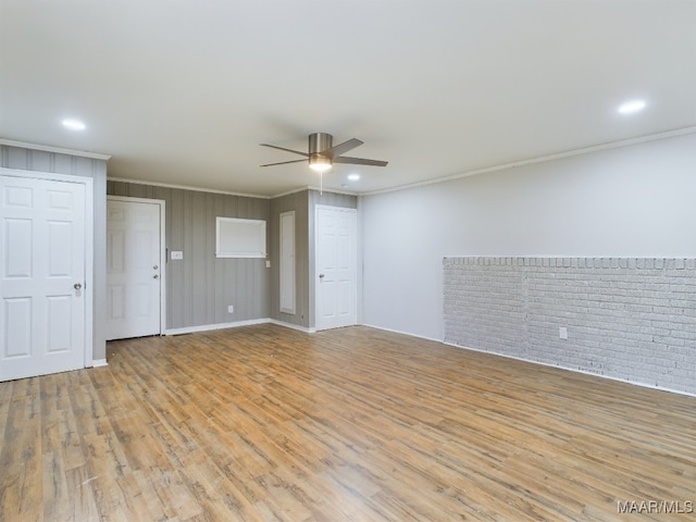 unfurnished room featuring crown molding, ceiling fan, brick wall, and light wood-type flooring