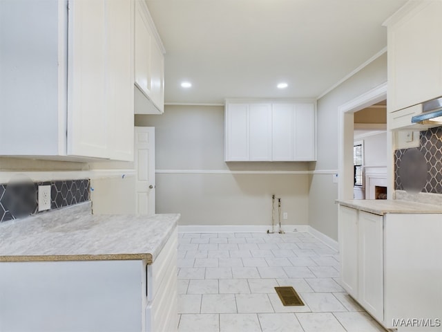 kitchen with white cabinetry, ornamental molding, and light tile patterned flooring