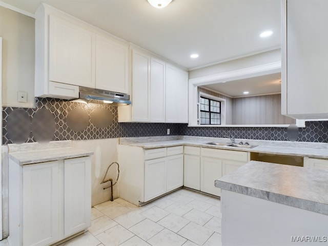 kitchen with tasteful backsplash, white cabinetry, and sink