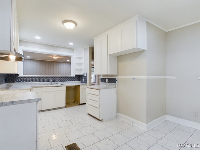 kitchen with tasteful backsplash, sink, white cabinets, and ornamental molding