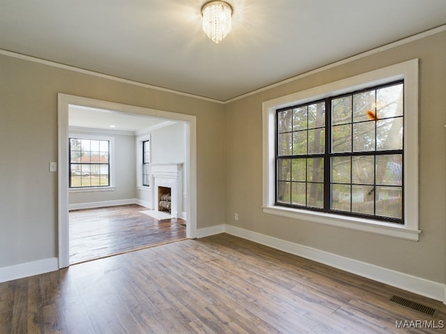 unfurnished living room featuring a chandelier, wood-type flooring, and ornamental molding