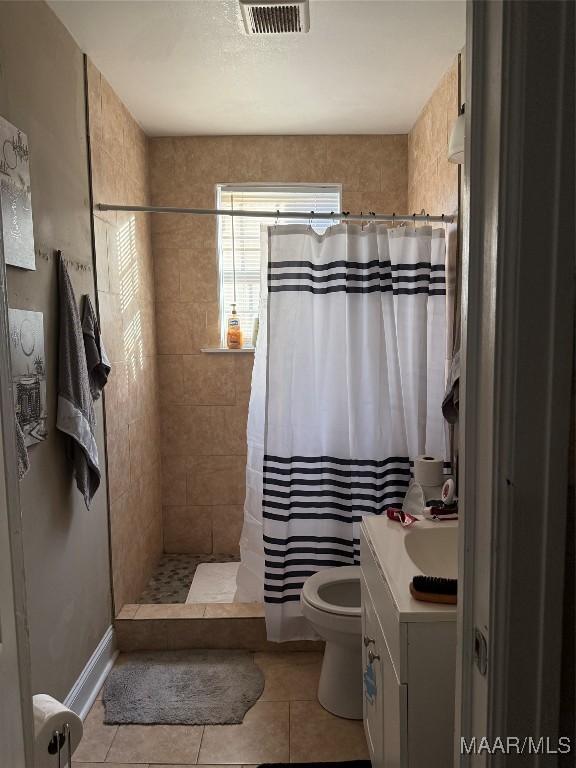 bathroom featuring tile patterned floors, vanity, toilet, and walk in shower