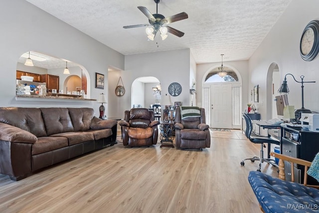 living room with a textured ceiling, light hardwood / wood-style flooring, and ceiling fan