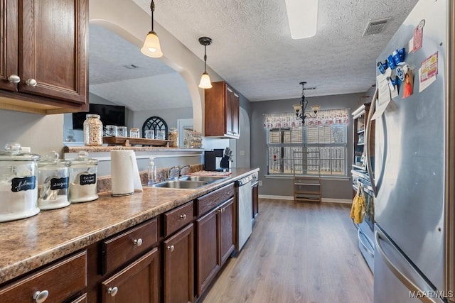 kitchen featuring sink, appliances with stainless steel finishes, decorative light fixtures, light hardwood / wood-style floors, and a chandelier