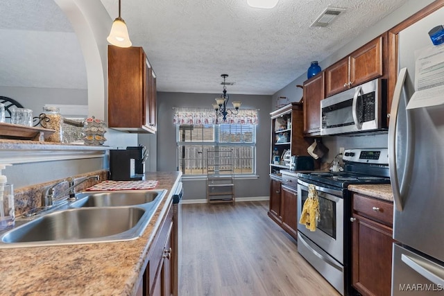 kitchen with pendant lighting, an inviting chandelier, sink, a textured ceiling, and appliances with stainless steel finishes