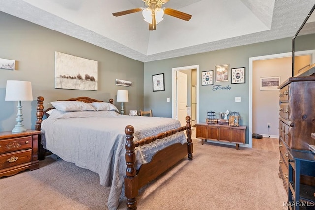 carpeted bedroom featuring ceiling fan, a raised ceiling, and a textured ceiling