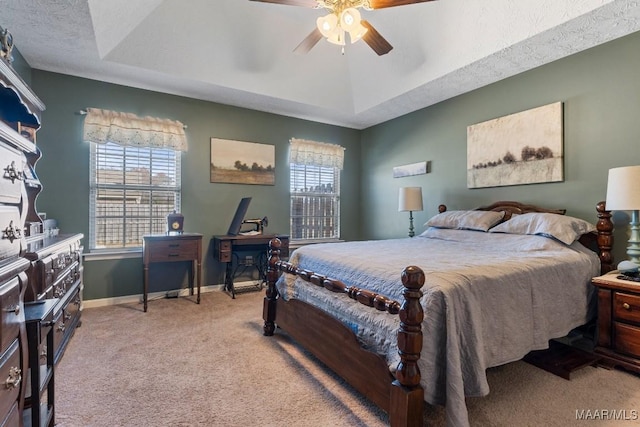 carpeted bedroom with ceiling fan, a raised ceiling, and a textured ceiling