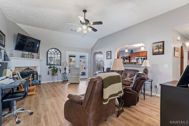 living room featuring lofted ceiling, ceiling fan, light hardwood / wood-style floors, and a textured ceiling