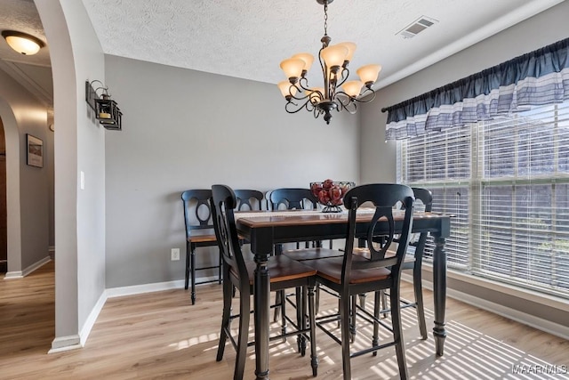 dining area featuring hardwood / wood-style flooring, a textured ceiling, and an inviting chandelier