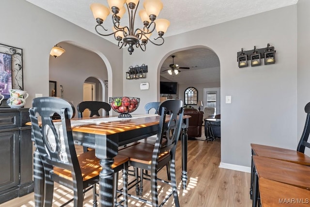 dining area with a textured ceiling, light hardwood / wood-style flooring, and ceiling fan with notable chandelier