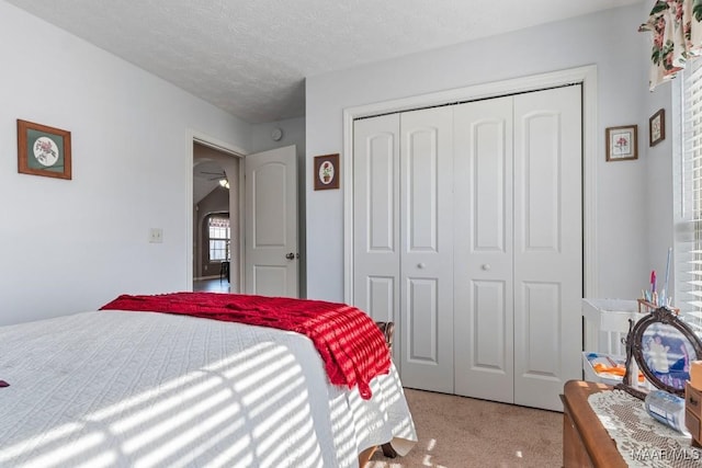 carpeted bedroom with a textured ceiling and a closet