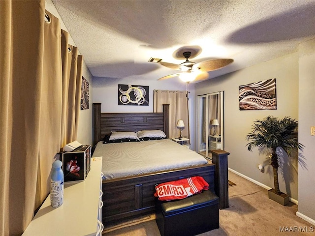 bedroom featuring a textured ceiling, light colored carpet, and ceiling fan