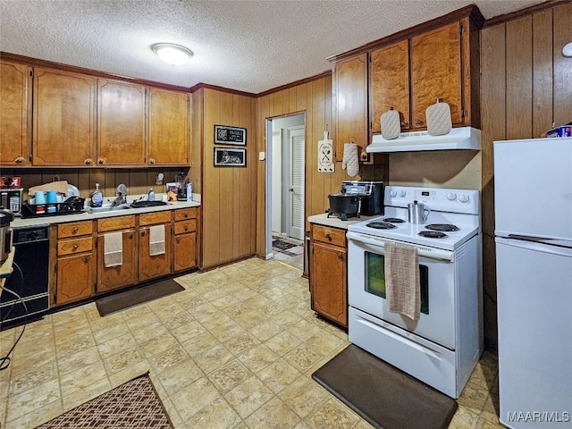 kitchen featuring wood walls, white appliances, sink, a textured ceiling, and extractor fan