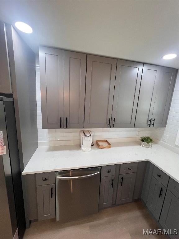 kitchen featuring gray cabinets, decorative backsplash, and stainless steel appliances